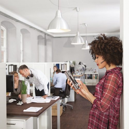 Woman in office using digital tablet with colleagues in background